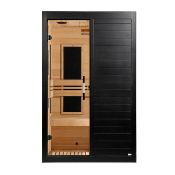 A modern infrared sauna with a black exterior door and a light wood interior featuring wooden benches and a tempered glass door.